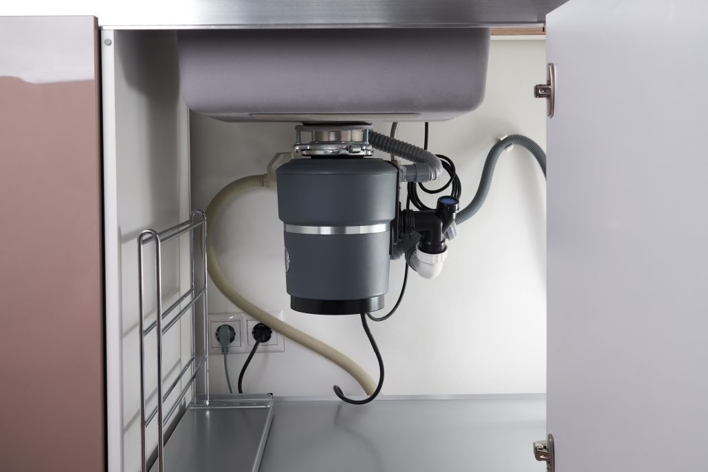 Plumber repairing a garbage disposal in a Santa Rosa kitchen